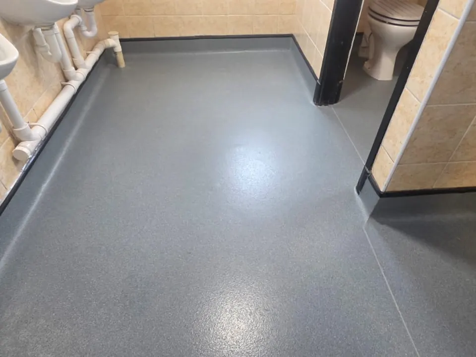 Grey safety flooring running into toilet cubicles with cap and cove skirting